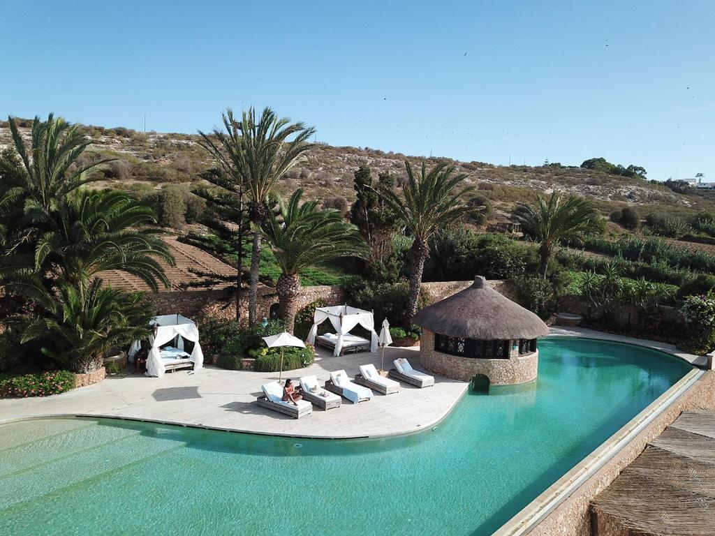 沃利迪耶拉苏丹娜沃利迪耶酒店的一个带椅子和凉亭的游泳池,并种植了棕榈树