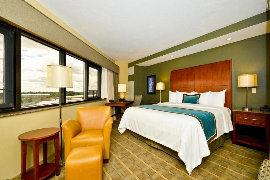 奥什科什Oshkosh Waterfront Hotel & Convention Center的配有一张床和一把椅子的酒店客房