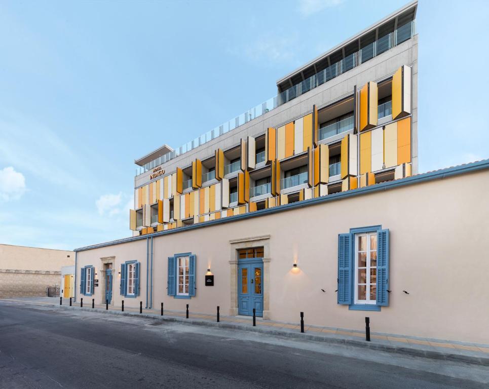 拉纳卡Hotel Indigo Larnaca, an IHG Hotel-ADULTS ONLY的街道上拥有蓝色和黄色窗户的建筑