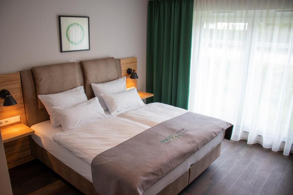 马克特奥伯多夫Trendic Hotel的一间卧室配有一张带绿色窗帘的大床