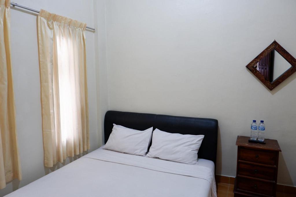 日惹Khresna Guest House Malioboro Mitra RedDoorz的一间卧室配有一张带黑色床头板的床和窗户