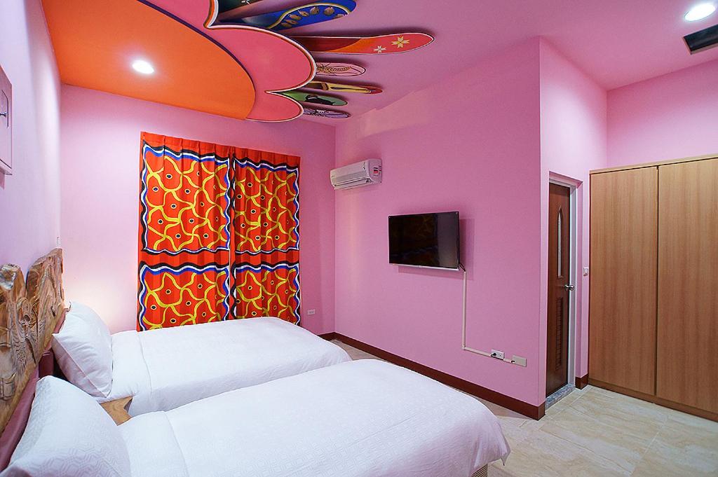 台东马卡巴嗨文创民宿的一间设有两张床和粉红色墙壁的客房
