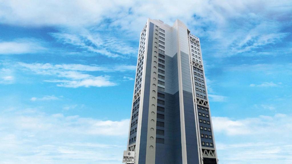 马尼拉Berjaya Makati Hotel的一座高大的白色建筑,背后是蓝天