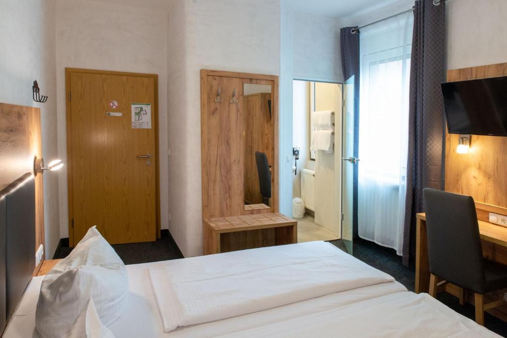 奥格斯堡费舍尔特尔酒店的酒店客房配有一张床、一张书桌和一台电视。