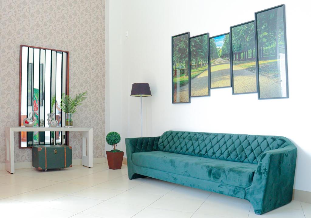 阿拉瓜伊纳Hotel Neblina的客厅里一张蓝色的沙发,墙上挂着绘画作品