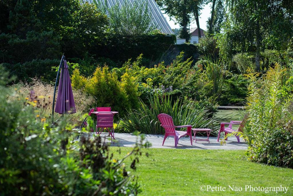 阿布维尔双桥花园酒店的花园内设有桌椅和遮阳伞