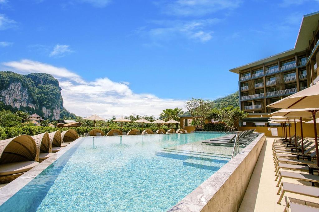 奥南海滩Centara Life Phu Pano Krabi-SHA Plus的一座带椅子的游泳池,背景是群山