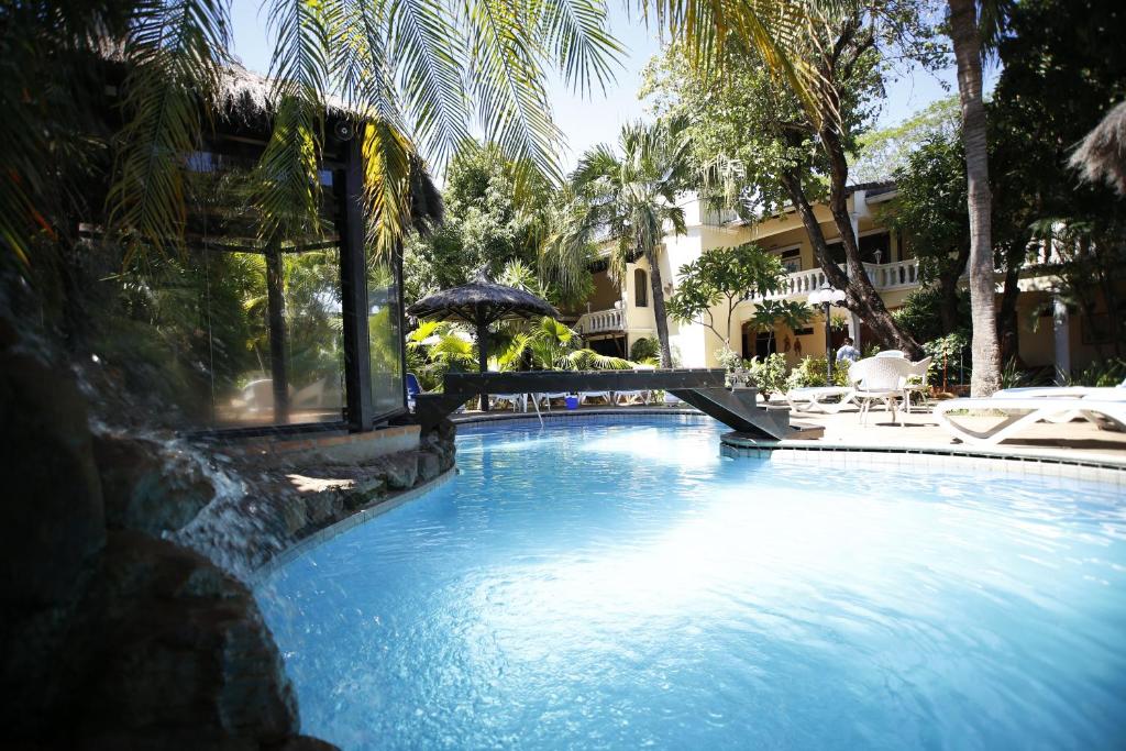 亚松森Paramanta Lifestyle Hotel的一座带遮阳伞和椅子的游泳池以及一座建筑