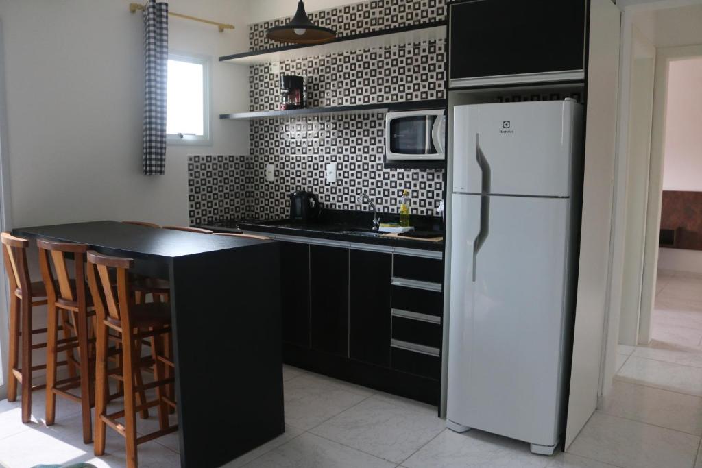 弗洛里亚诺波利斯Nosso Cantinho Canasvieiras的厨房配有白色冰箱和黑色台面