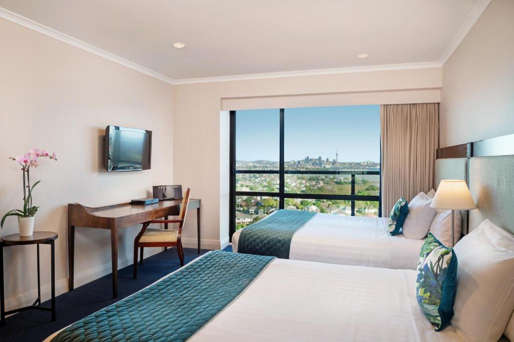 奥克兰The Spencer Hotel的酒店客房设有两张床、一张书桌和一个窗户。