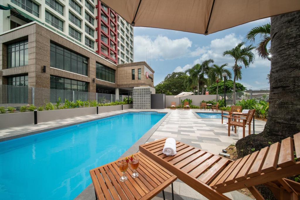 怡保Travelodge Ipoh的一座带桌椅的游泳池和一座建筑