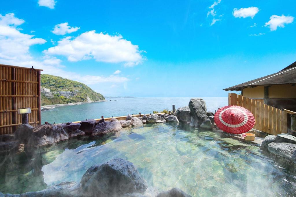 热海水叶亭大江户温泉物语酒店(Ooedo Onsen Monogatari Hotel Suiyotei)的一个带岩石和遮阳伞的游泳池