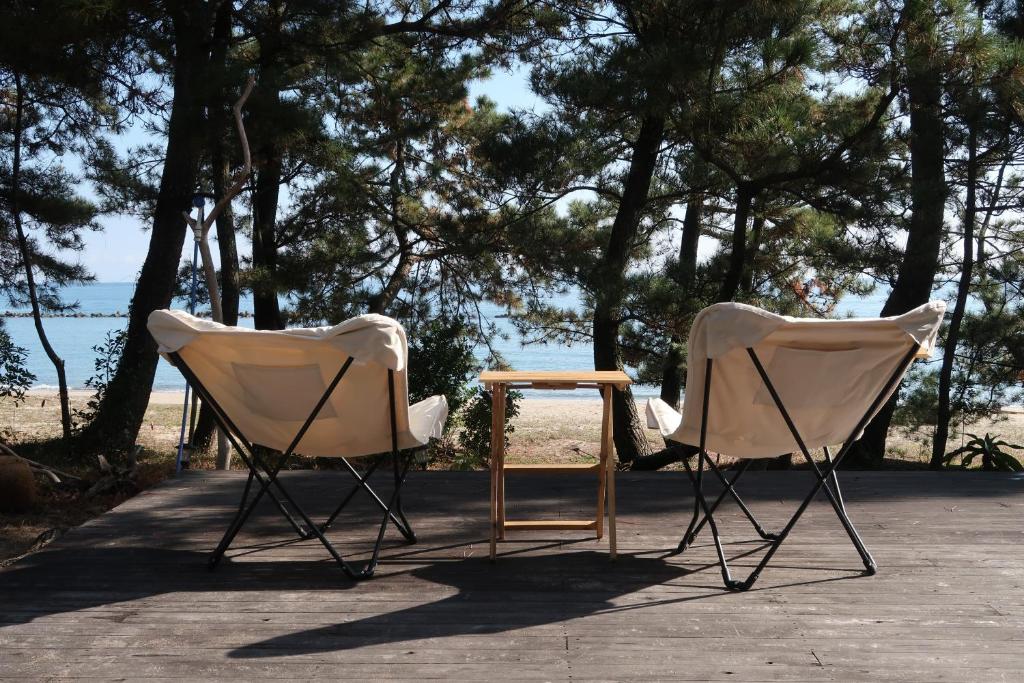 Kitsuki奈多みどり荘 Nada Beach House的海滩前的两把椅子和一张桌子