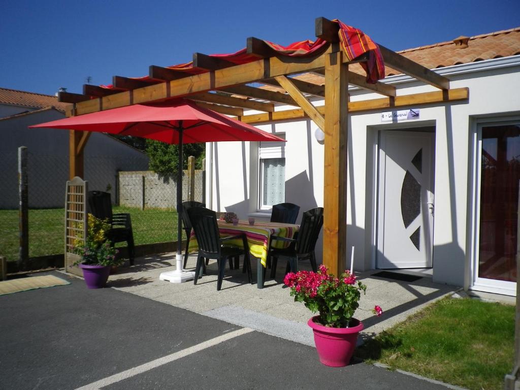 莱萨布勒-多洛讷海洋公寓酒店的一个带桌子和红色遮阳伞的庭院