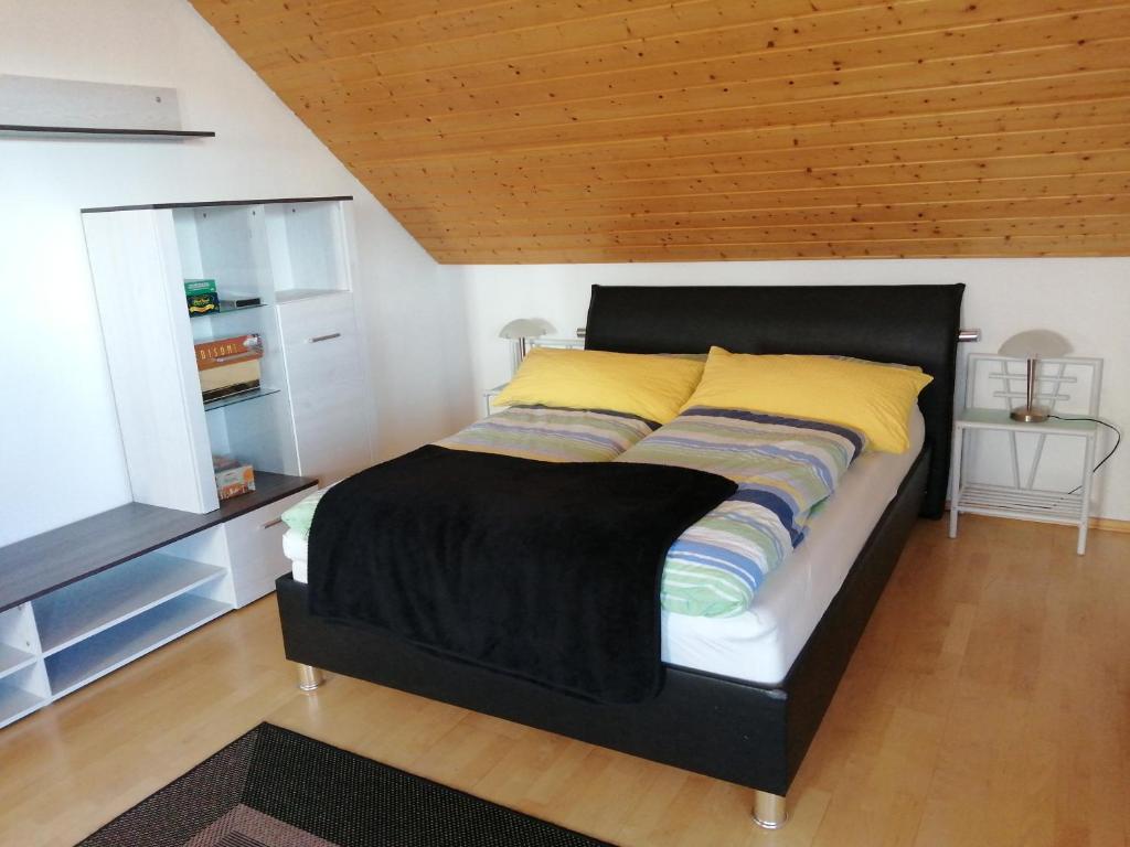 德根多夫Schöne Wohnung in Deggendorf für 1 bis 5 Personen的一张带黑色床头板和黄色枕头的床
