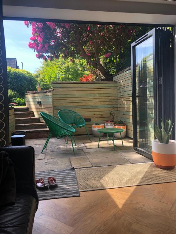 曼彻斯特Chorlton Garden Rooms. Relax, work, stay and play.的一个带绿色椅子和桌子的庭院