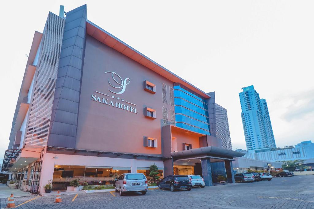 SunggalSaka Hotel Medan的前面有汽车停放的建筑
