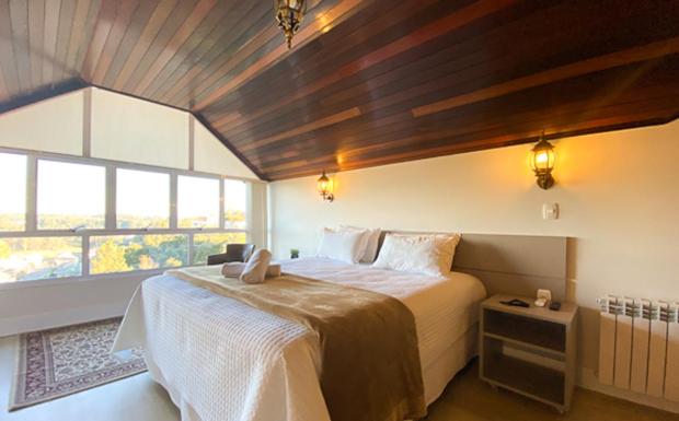 弗洛里斯-达库尼亚Letto Hotel Flores da Cunha的一间卧室设有一张大床和一个大窗户