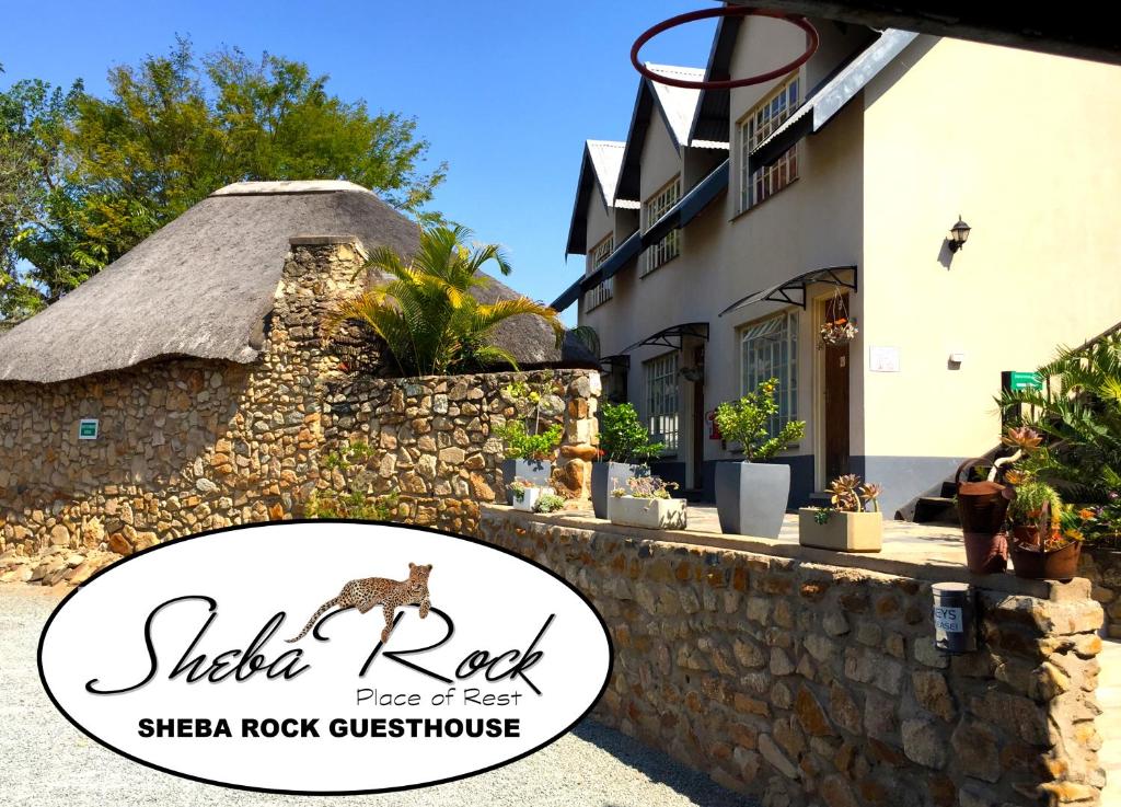 内尔斯普雷特Sheba Rock Guesthouse的石墙旁羊石屋的标志