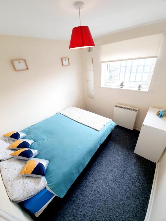 雷利Rayleigh Town Centre 3 Bedroom Apartment的一间卧室配有一张蓝色的床和红灯