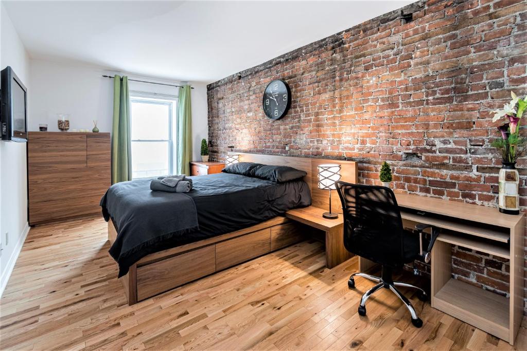 魁北克市Le Théâtral - En plein coeur de l'action avec stationnement的一间卧室设有砖墙、一张床和一张书桌