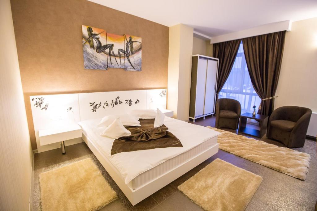 克拉约瓦梅利沙酒店的卧室配有一张白色大床和两把椅子
