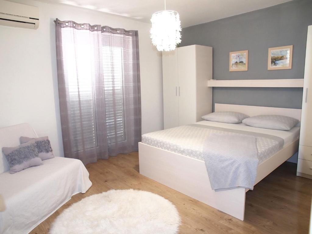 马卡尔斯卡Apartmani Igor的一间白色卧室,配有两张床和吊灯