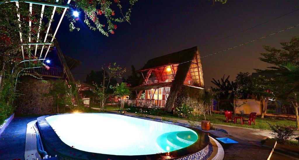 芹苴Mekong Delta Ricefield Lodge的夜间在房子前面的游泳池