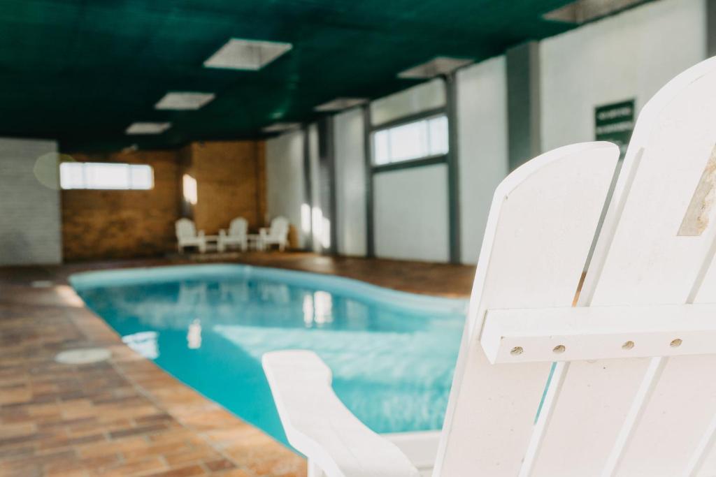 阿米代尔Deer Park Motor Inn Armidale的游泳池旁带白色椅子的游泳池