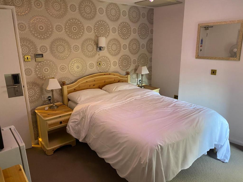 特伦特河畔伯顿三皇后酒店的卧室配有一张白色大床和镜子