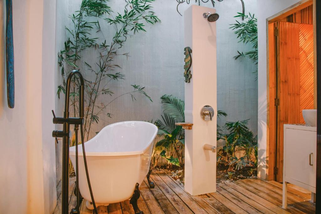 爱妮岛SANSE Boutique Hotel的带浴缸的浴室,墙上有植物
