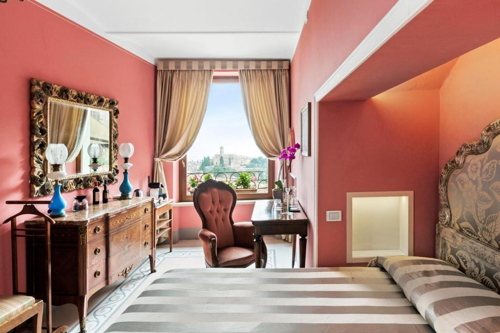 锡耶纳Residenza d'Epoca Palazzo Borghesi的卧室设有红色的墙壁、书桌和床。