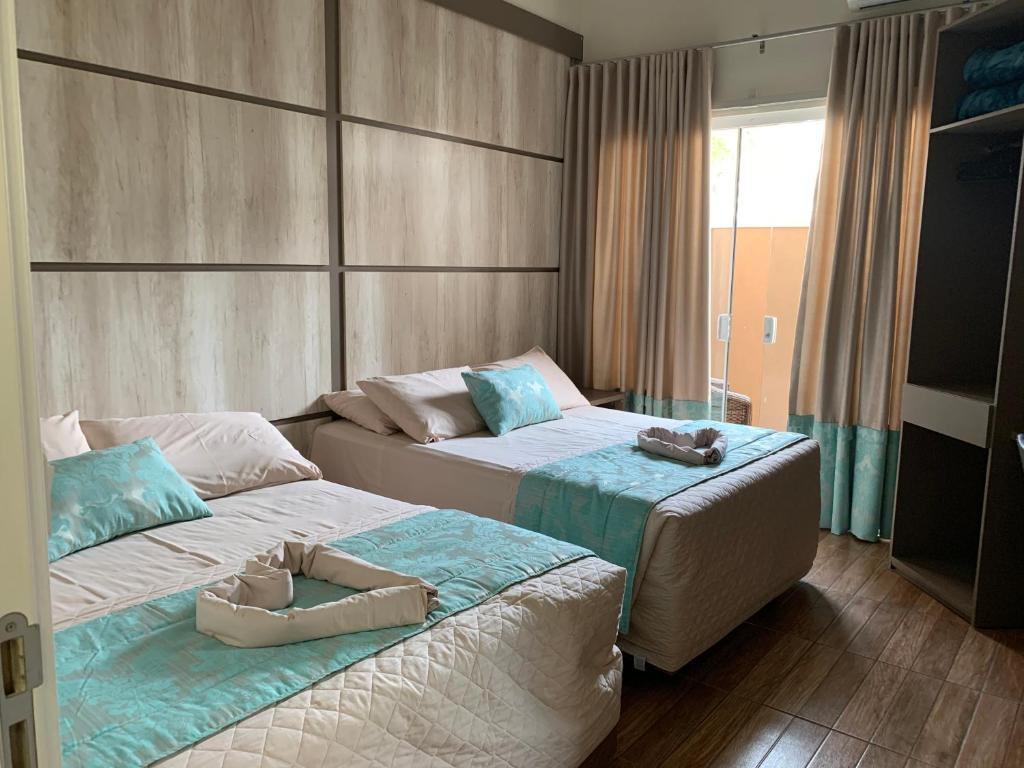 佩尼亚Pousada Duas Ilhas的两张位于酒店客房的床,配有毛巾