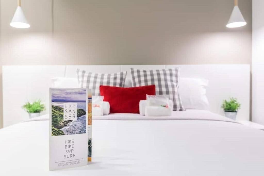 圣塞瓦斯蒂安BUENPAS的卧室配有白色的床和红色枕头