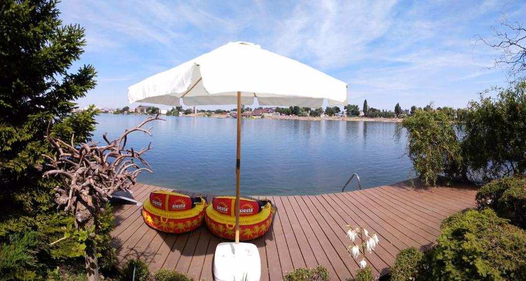 塞内奇TopSenec-Lakeside Home的两把椅子和一把雨伞在水边的码头上