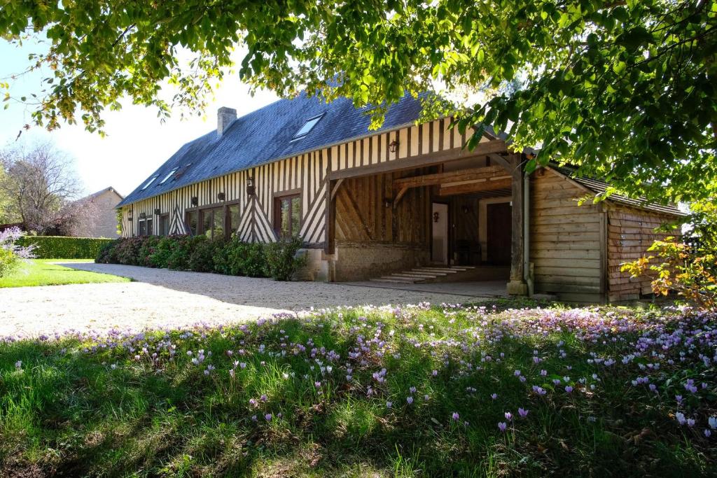 Biéville-en-AugeMaison "Le Pressoir" avec Grand Jardin的前面一个种着紫色花的谷仓