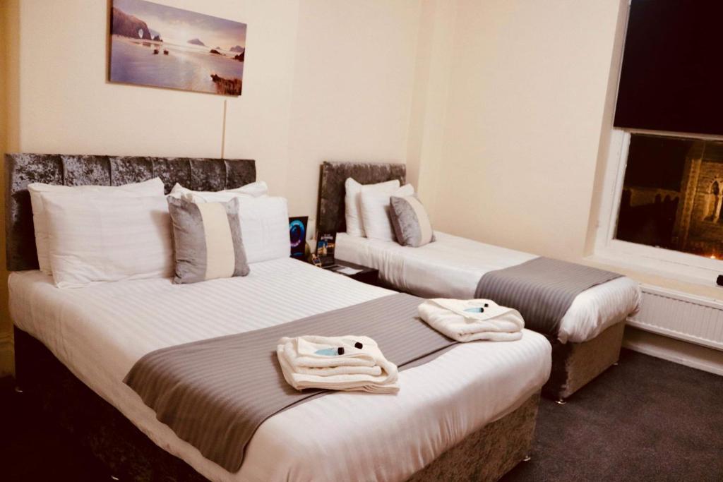 兰迪德诺The New Alexandra Hotel的两张位于酒店客房的床,配有毛巾