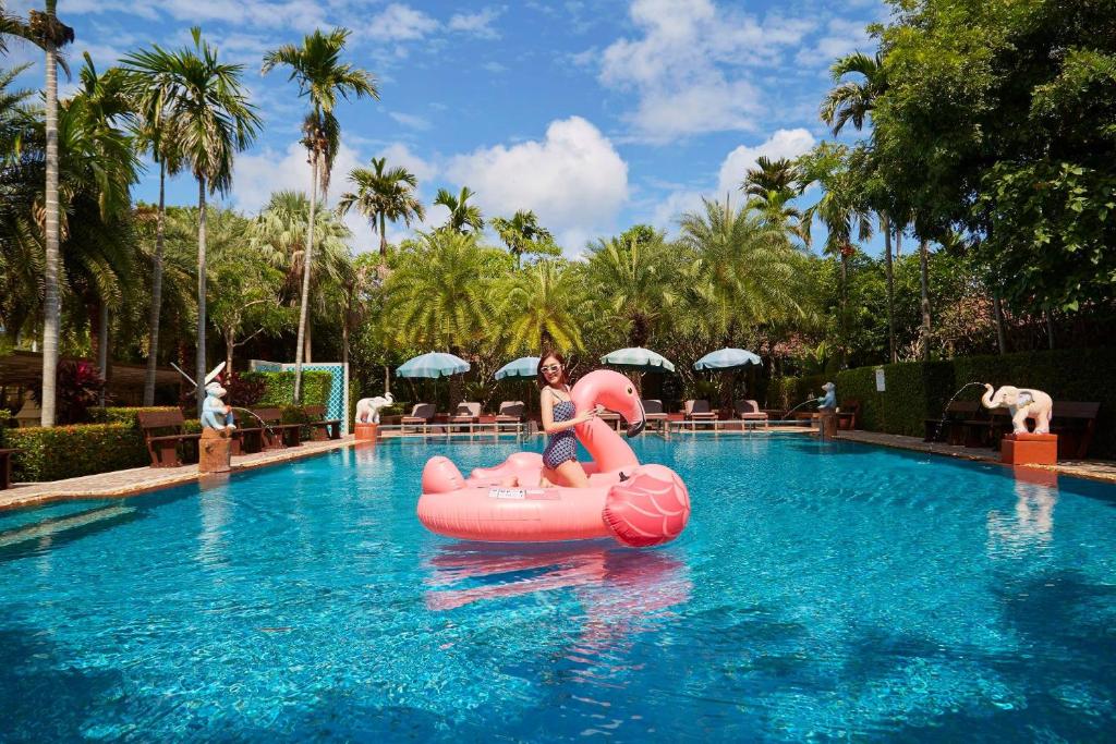北芭堤雅沃尼达别墅花园度假酒店的妇女在游泳池里用粉红色木筏骑着