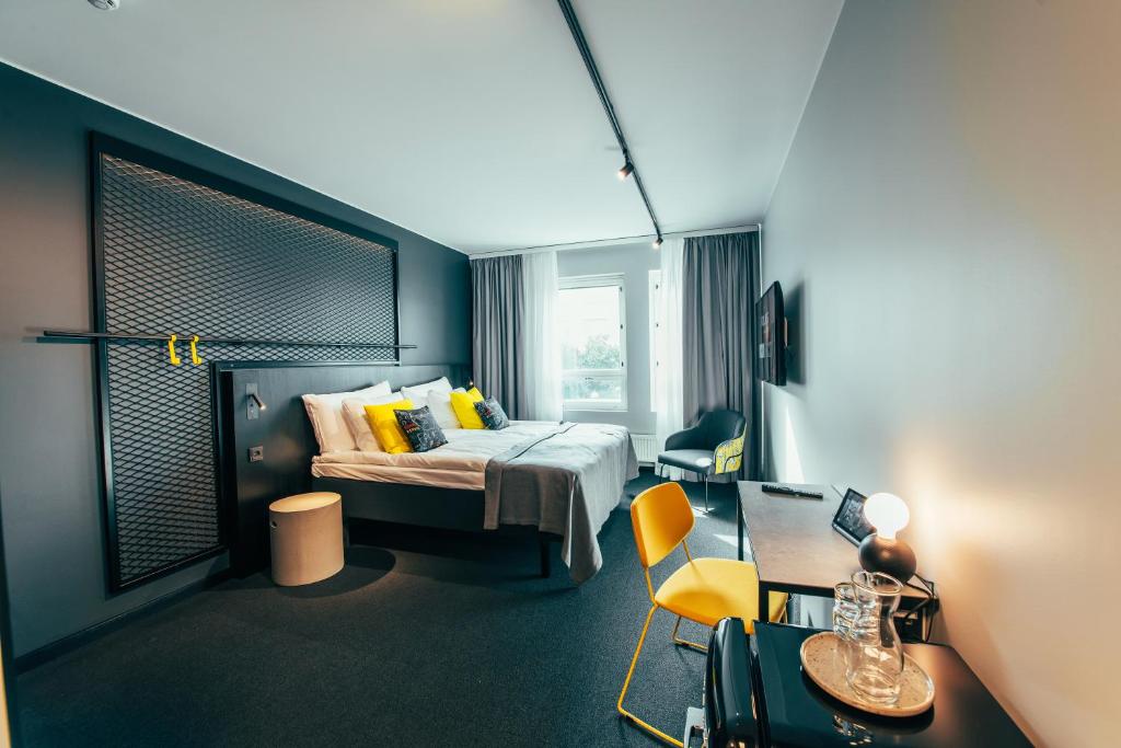 赫尔辛基The Folks Hotel Konepaja的酒店客房配有一张床、一张桌子和一把椅子。