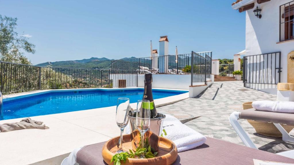 蒙达Casa Guajar 2 Monda by Ruralidays的游泳池畔的桌子上放一瓶葡萄酒