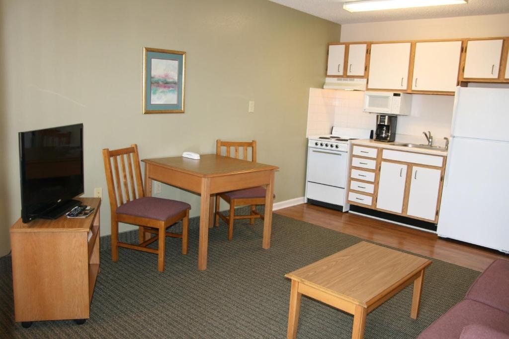 索尔兹伯里索尔兹伯里实惠套房酒店的客厅设有厨房、桌椅和冰箱。