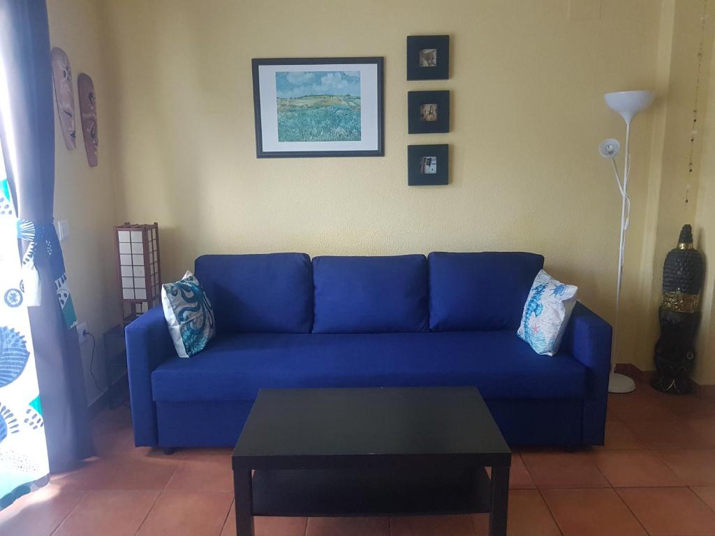 卡拉圣维森特Casa Beatriz的客厅配有一张蓝色的沙发,配有一张桌子