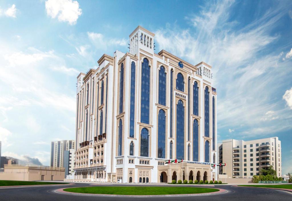 迪拜Al Jaddaf Rotana Suite Hotel的白色的大建筑,设有蓝色的窗户