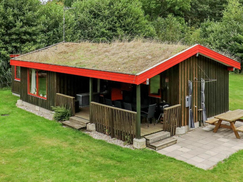 莱斯Holiday home Læsø XXV的一座带草屋顶的小房子,设有庭院