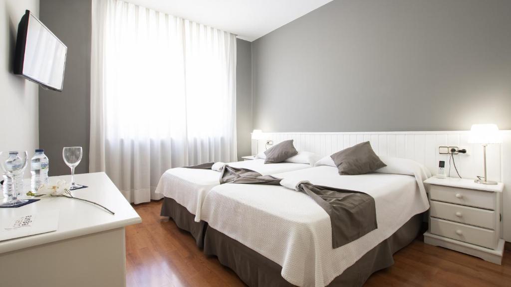 特鲁埃尔伊莎贝尔塞古拉酒店的一间卧室设有两张床、一张桌子和一个窗口