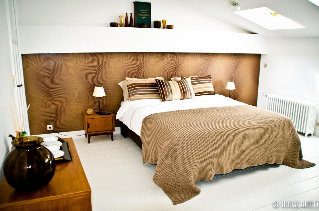 布鲁塞尔九十家住宿加早餐旅馆的一间卧室设有一张大床和一个木制床头板