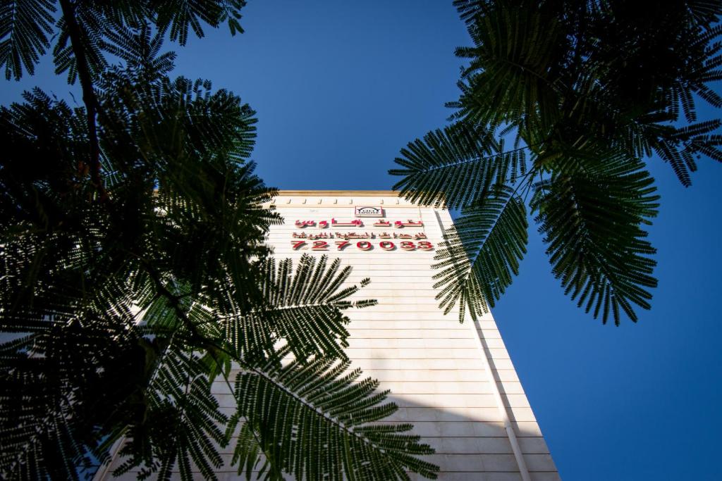 塔伊夫Toot House ALQAIM的一座高大的建筑,前面有棕榈树