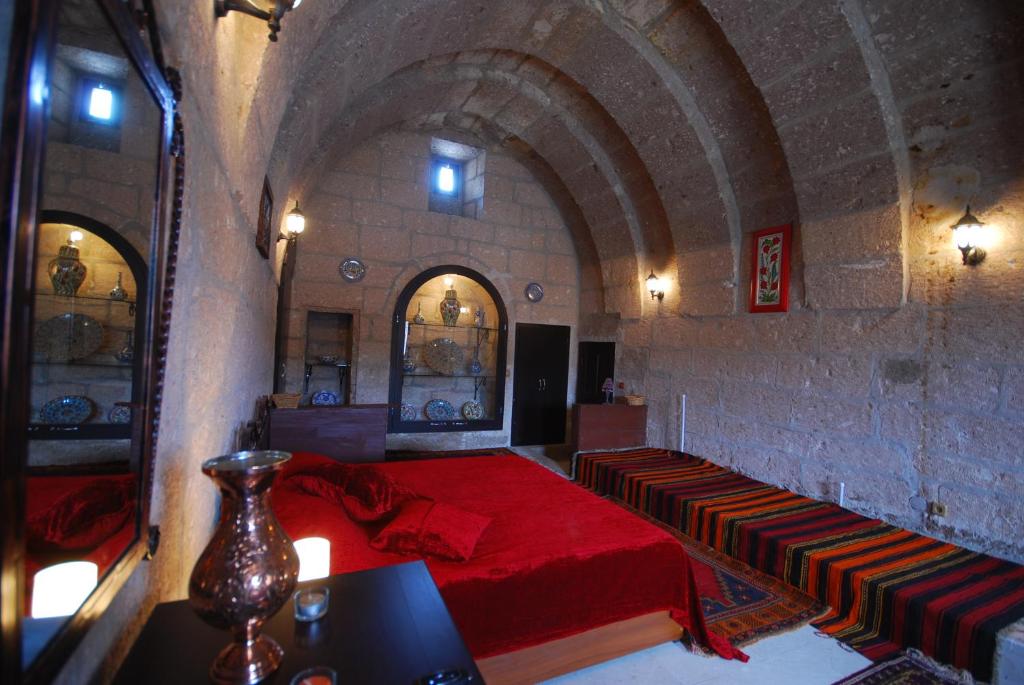 Guzelyurt卡拉曼利大厦酒店的一间石墙卧室,配有红色的床