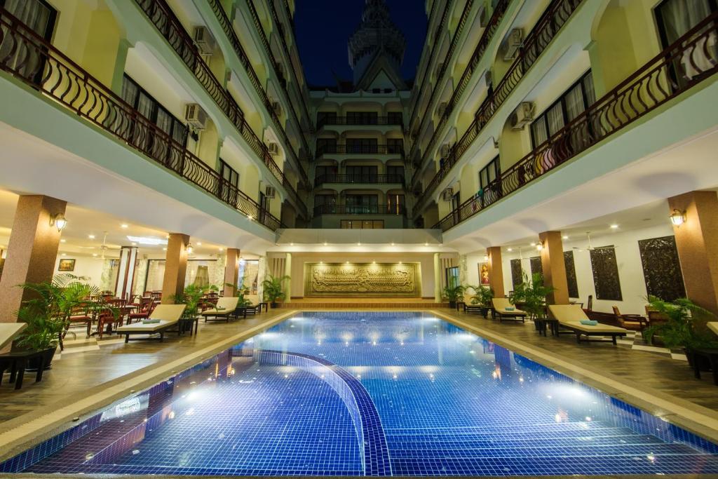 暹粒Smiling Deluxe Hotel的酒店设有一个室内游泳池,配有桌椅