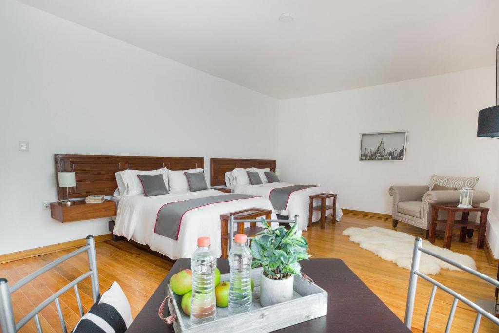 圣路易斯波托西Azabu Hotel Collection的一间卧室设有两张床和一张桌子,备有饮料